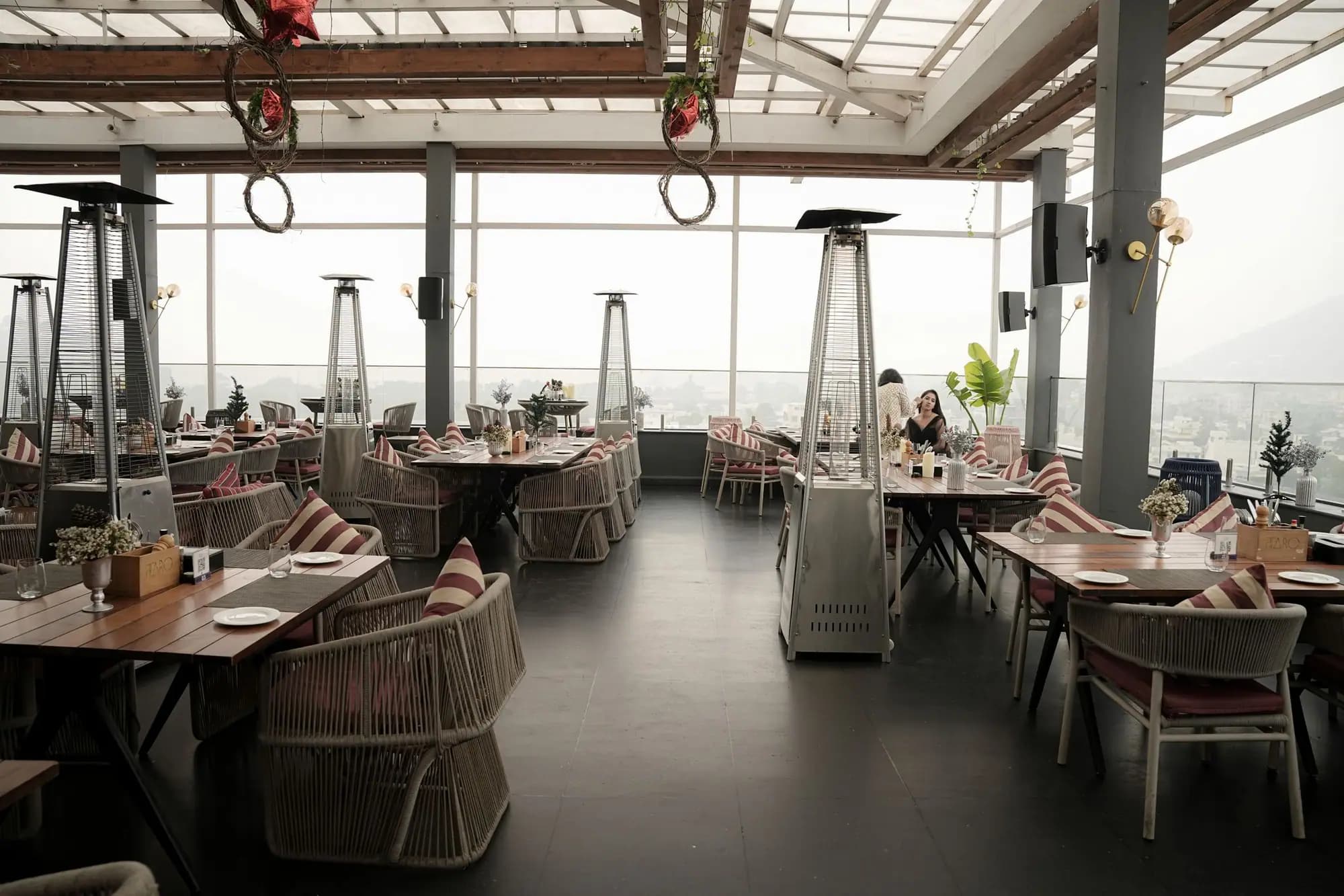 An empty rooftop dining terrace with a city view.