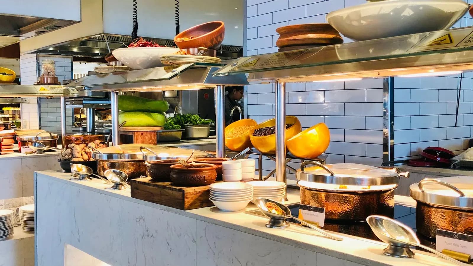 Indian dishes in chafing dishes on a buffet line.